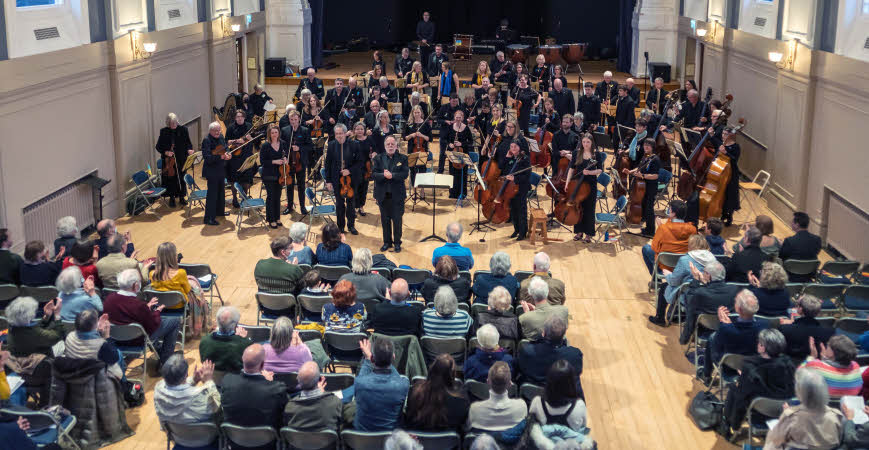 The orchestra on their feet in front of an appreciative audience in Alington Hall at the end of the concert.